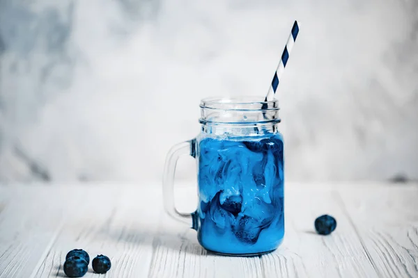 Trendy butterfly pea tea with milk and ice on marble background.