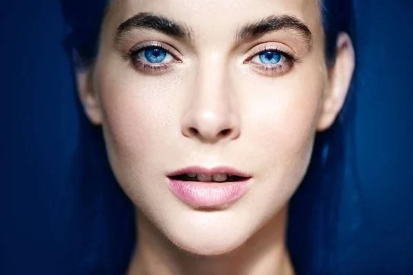 Retrato de bela mulher de olhos azuis no fundo azul . — Fotografia de Stock