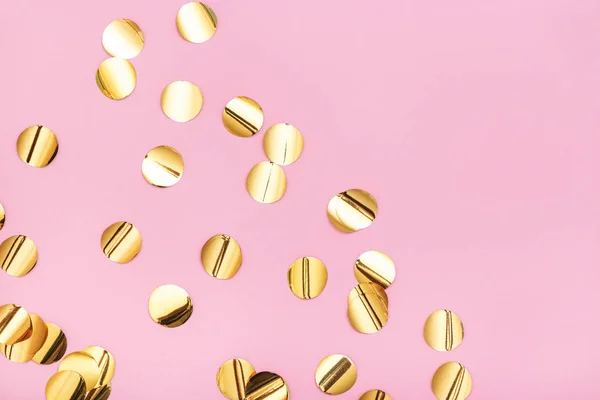 Primer plano de confeti metálico dorado sobre fondo rosa pastel . —  Fotos de Stock