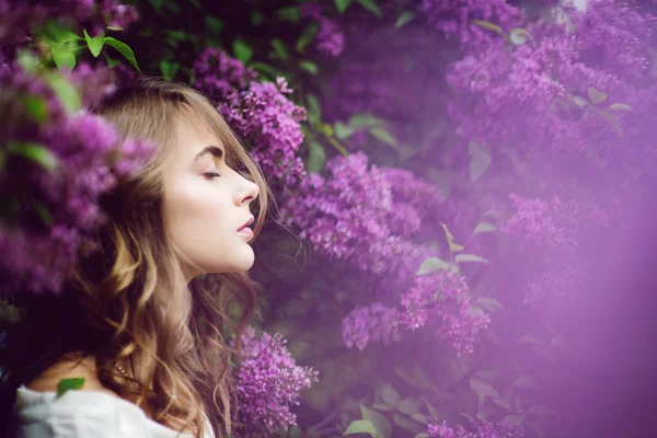 Hermosa joven con los ojos cerrados rodeada de lila . Imagen de stock