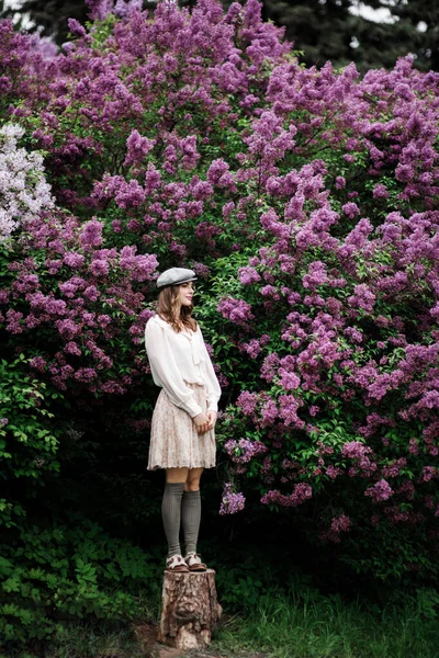 Hermosa joven de pie cerca de lilas florecientes . —  Fotos de Stock