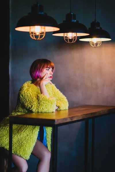 穿着黄色人造毛皮外套坐在酒吧里的漂亮女人. — 图库照片
