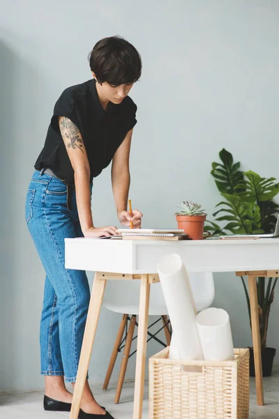 机の近くに立ってノートを取る若いビジネス女性. — ストック写真