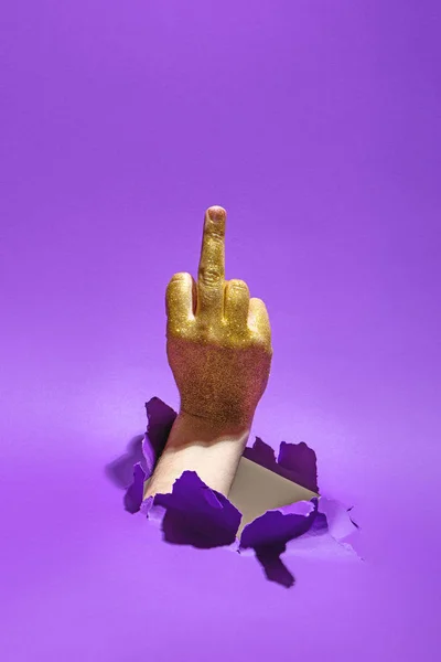 Hombre gesto de la mano con el dedo medio a través del agujero de papel sobre fondo violeta . — Foto de Stock