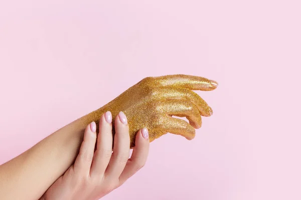 Mükemmel manikür, moda tırnak sanatı ve pembe arka planda altın parıltılı el..