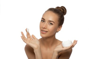 Beautiful young woman with facial cream in her hands isolated on white.
