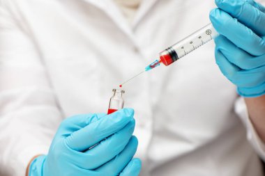 Tıbbi eldivenli doktor şırıngaya aşı enjekte ediyor..