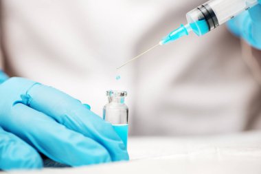 Doktor elinde şırınga ve aşı olan mavi eldivenleri teslim etti..