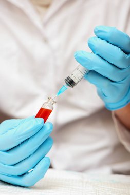 Tıbbi eldivenli doktor şırıngaya aşı enjekte ediyor..