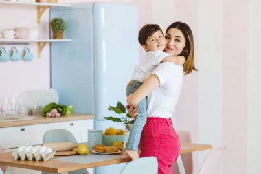 Güzel anne ve küçük oğlu mutfakta sarılıyorlar..
