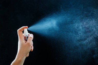 Siyah arka planda antibakteriyel el spreyi kullanma..
