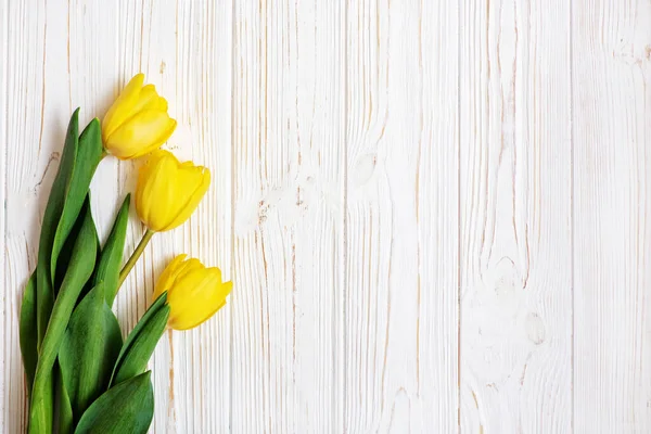 Fresh beautiful yellow tulips on white wooden background. — Stock Photo, Image