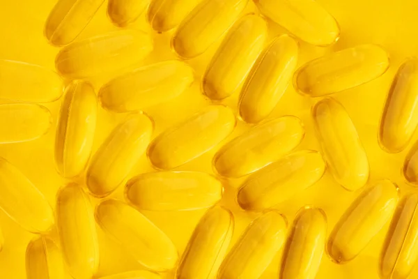 Tobolky rybího tuku na žlutém pozadí — Stock fotografie