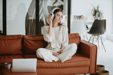 Kanepede oturan ve müzik dinleyen bir kadın..