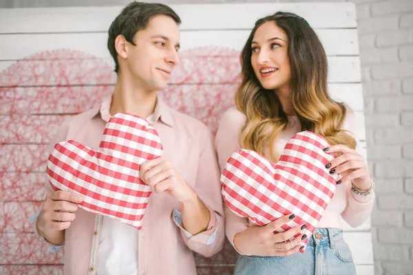 Young couple with heart-shaped pillows posing for love-story in — Stock Photo, Image