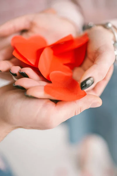Mãos de macho e fêmea com fundo de confete em forma de coração vermelho — Fotografia de Stock
