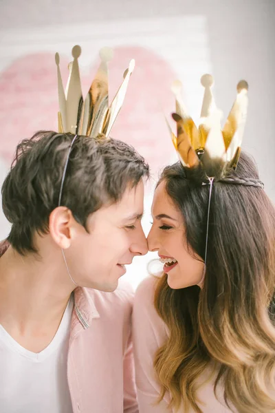 Jovem casal com coroas beijando em estúdio decorado — Fotografia de Stock