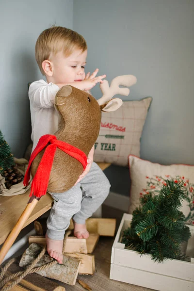 Jeune garçon jouant avec le cerf jouet dans la chambre décorée de Noël — Photo