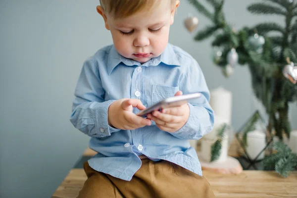 Jeune garçon mignon bébé avec smartphone dans la chambre décorée de Noël — Photo