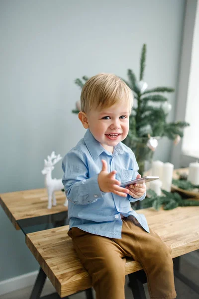 Jovem menino bonito com smartphone no quarto decorado de Natal — Fotografia de Stock