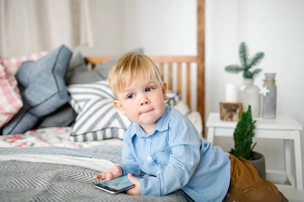 Jovem menino bonito com smartphone no quarto decorado de Natal — Fotografia de Stock