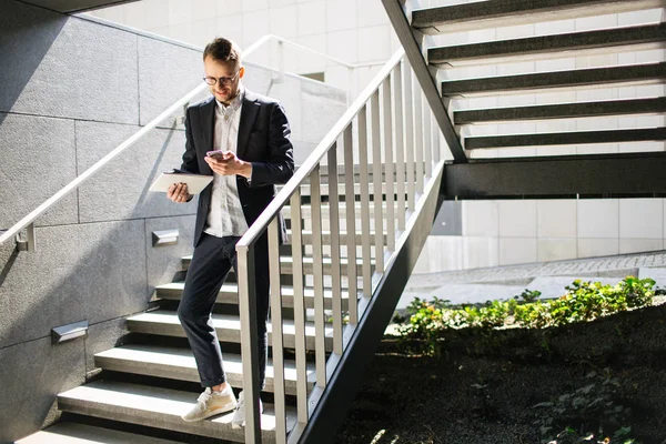 Hipster hombre de negocios en traje y gafas con tablet smartphone o —  Fotos de Stock