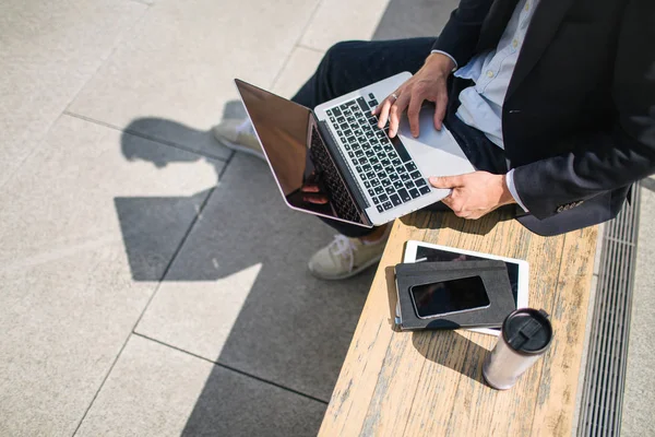 Young hipster businessman in suit typing laptop near office outd — Stock Photo, Image