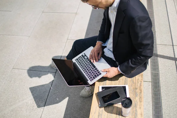 Joven hombre de negocios hipster en traje de escribir portátil cerca de la oficina outd —  Fotos de Stock