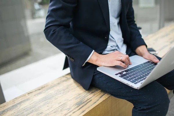 Young hipster businessman in suit typing laptop near office outd — Stock Photo, Image