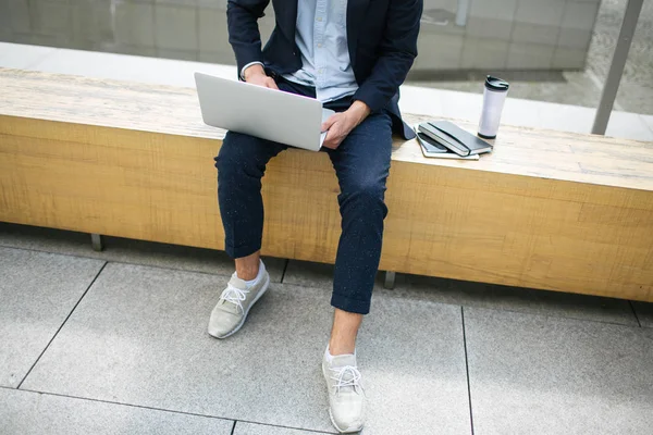 Jovem homem de negócios hipster em terno digitando laptop perto de escritório outd — Fotografia de Stock