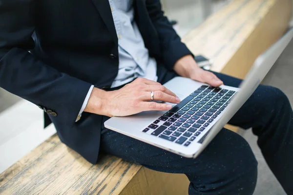 Young hipster businessman in suit typing laptop near office outd — Stock Photo, Image