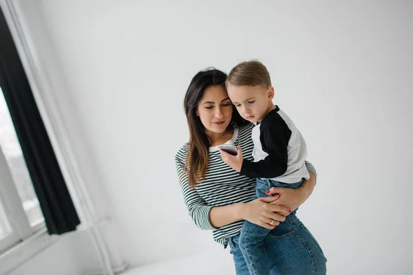 Young mother and baby boy with smartphone over white background — Stock Photo, Image