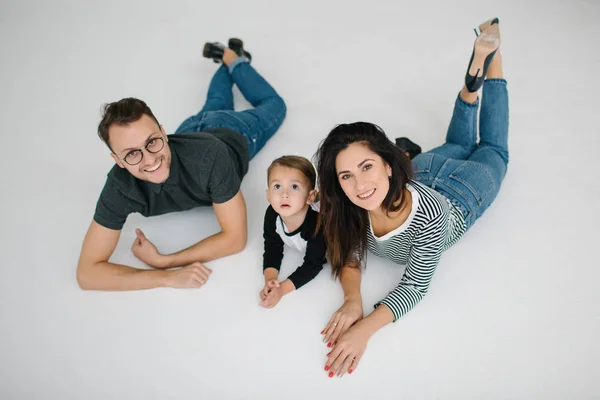 Hipster father, mother lying with baby boy on white background — Stock Photo, Image