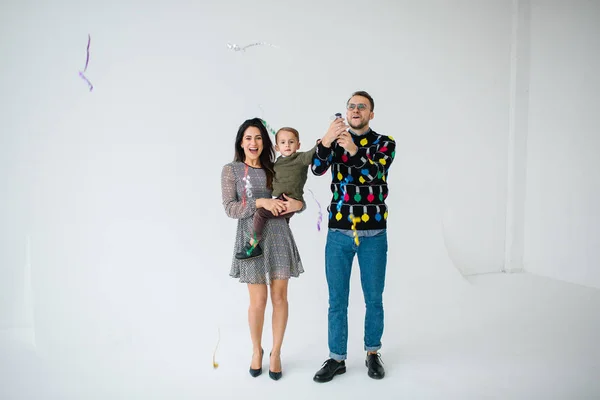 Young couple with son celebrating with confetti over white background — Stock Photo, Image