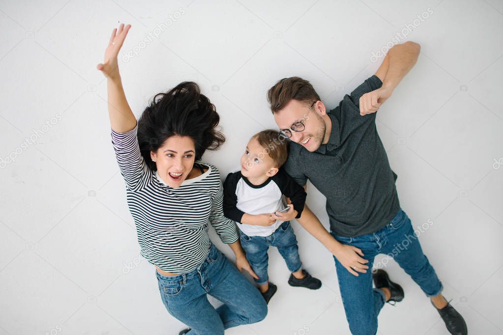 Hipster father, mother lying with baby boy on white background