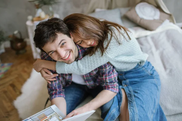 Joven pareja hipster leyendo revista en cama hecha a mano con sueño — Foto de Stock