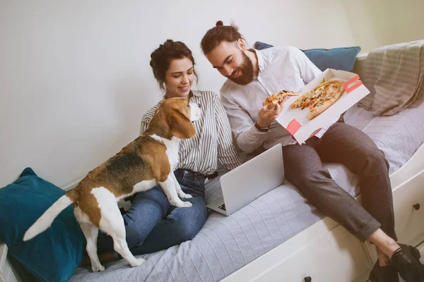 Para młoda hipster domu jedzenie pizzy z laptopa i pies — Zdjęcie stockowe