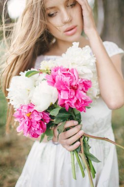 Açık havada çiçekli beyaz elbiseli güzel genç kadın