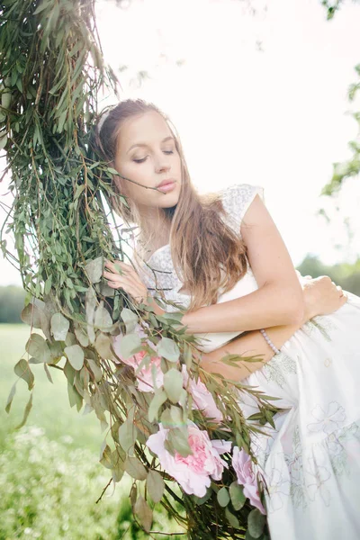 Hermosa mujer en vestido blanco en swing al aire libre con flores —  Fotos de Stock