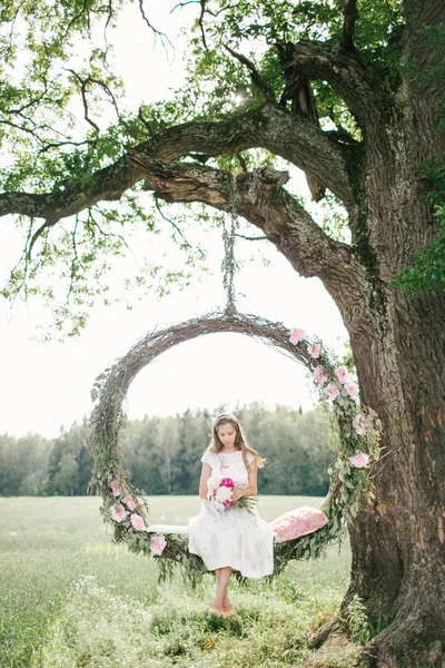 Hermosa mujer en vestido blanco en swing al aire libre con flores — Foto de Stock