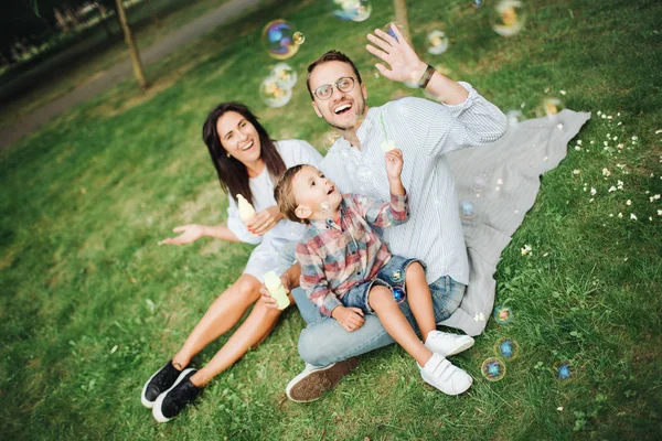 屋外の公園でバブル ワンドで遊んで幸せな若い家族 — ストック写真