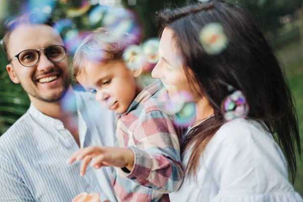 Buborék pálca parkban kint játszik a boldog fiatal család — Stock Fotó