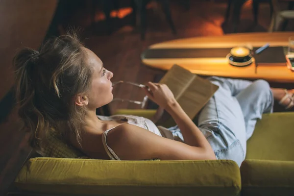 Jonge mooie Kaukasische vrouw leesboek in café het dragen van eyegla — Stockfoto