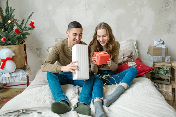 Young caucasian couple unboxing presents laying on bed — Stock Photo, Image