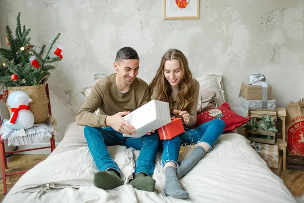 Young caucasian couple unboxing presents laying on bed — Stock Photo, Image