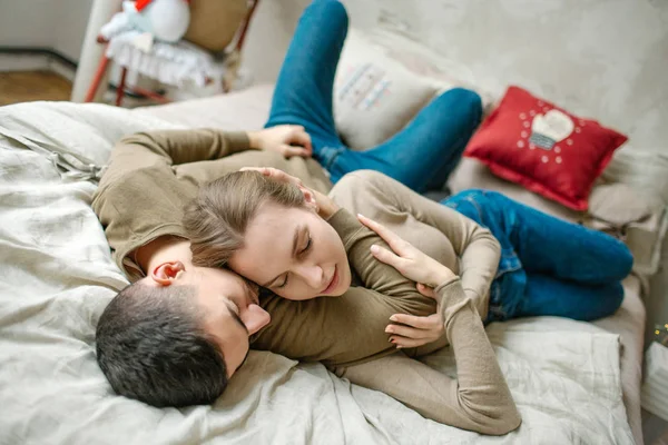 Jovem abraçando atraente mulher encaracolada na cama — Fotografia de Stock