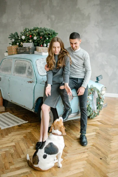 Young couple with beagle and retro car in decorated studio — Stock Photo, Image