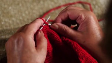 Büyükanne bir şöminenin önünde oturan bir kazak dokuma kumaşlar