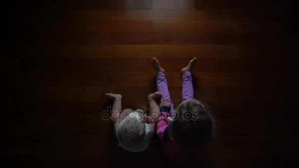 Kis testvér a testvérével, nézi a televíziót, ül a sötétben — Stock videók