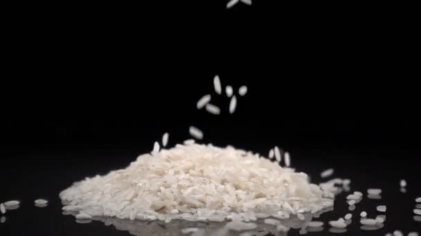 O arroz cai em uma superfície preta sólida — Vídeo de Stock